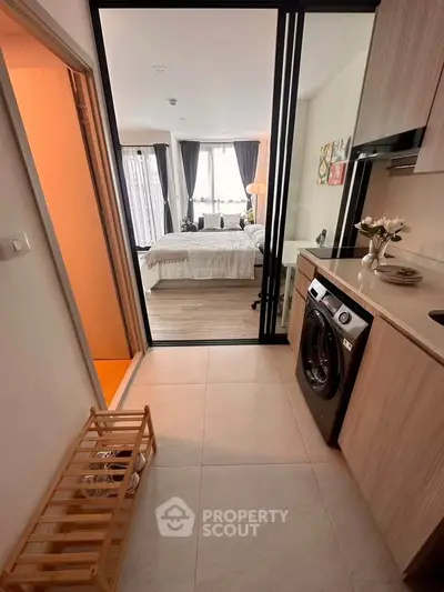 Modern apartment with compact kitchen and cozy bedroom featuring natural light and stylish decor.