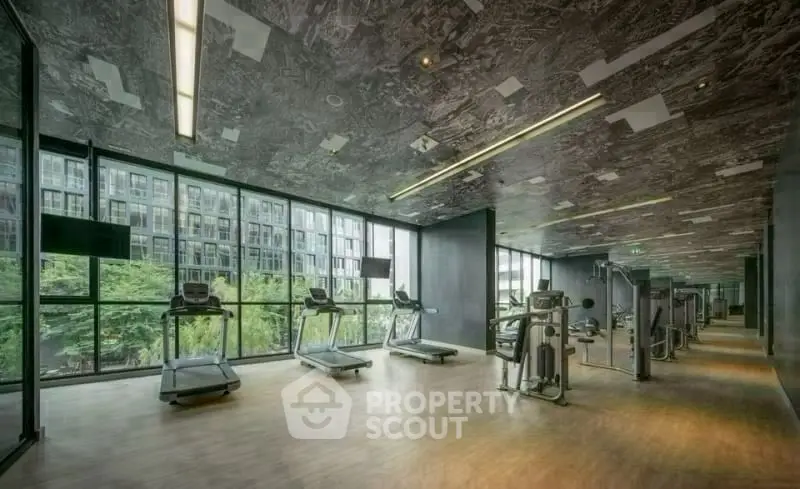 Modern gym with large windows and fitness equipment in a luxury building.