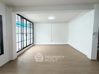 Spacious empty room with large windows and wooden flooring, perfect for customization.