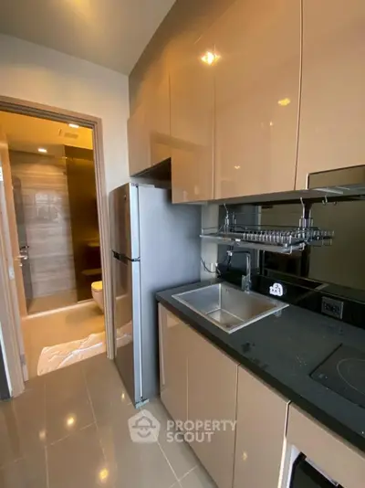 Modern kitchen with sleek cabinetry and stainless steel appliances adjacent to a stylish bathroom.