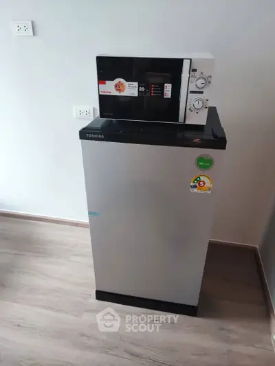 Compact kitchen setup with modern microwave and fridge in sleek design.