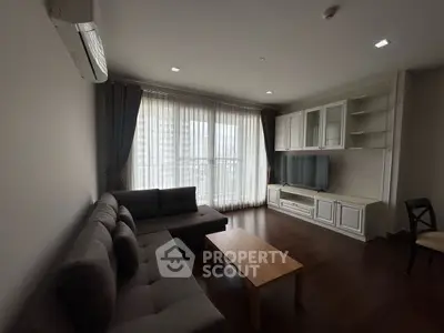 Spacious living room with modern furniture and large windows in a high-rise apartment.