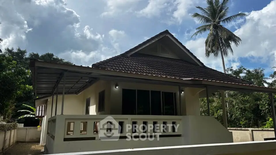 Charming tropical house with a spacious porch and lush greenery.