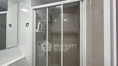 Modern bathroom with glass shower enclosure and sleek tile design.