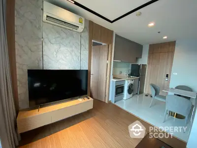 Modern studio apartment with sleek wooden flooring, fully-equipped kitchen, and a large flat-screen TV, perfect for urban living.