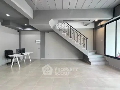 Modern open-plan office space with sleek staircase and minimalist design.