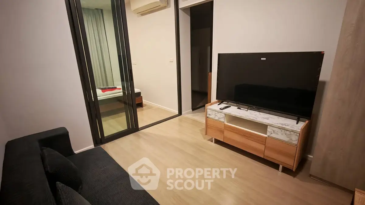 Modern living room with sleek TV stand and cozy sofa, adjacent to a stylish bedroom.