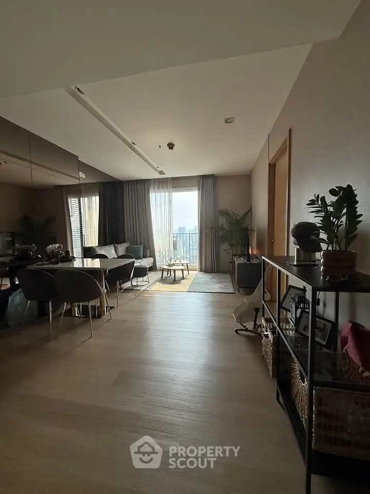 Spacious modern living room with large windows and city view, elegant decor and natural light.