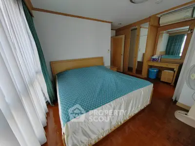 Spacious bedroom with wooden flooring and large bed in modern apartment