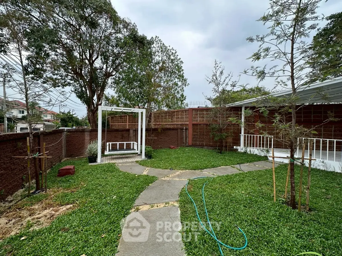 Charming garden with lush greenery and paved walkway in a serene residential area.