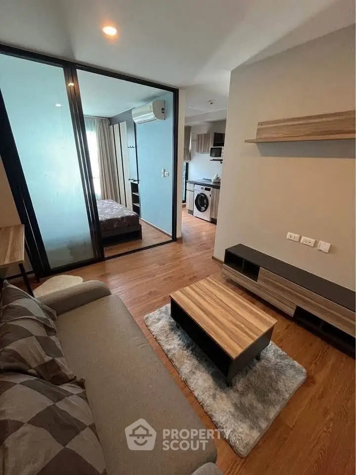 Modern apartment interior with cozy living room and view into bedroom and kitchen.