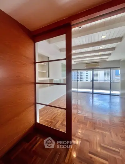 Spacious living room with wooden flooring and large windows offering city views