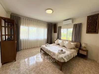 Spacious bedroom with elegant decor and large windows offering natural light.