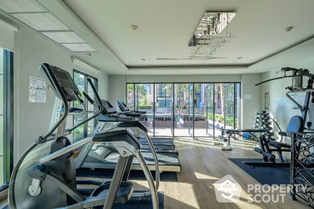 Modern gym with state-of-the-art equipment and large windows overlooking lush greenery.