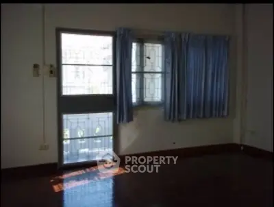 Spacious room with natural light and blue curtains, ideal for customization.
