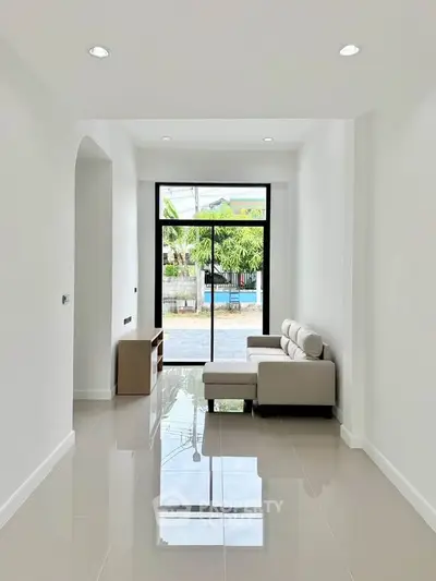 Modern living room with sleek furniture and large windows offering natural light and garden view.