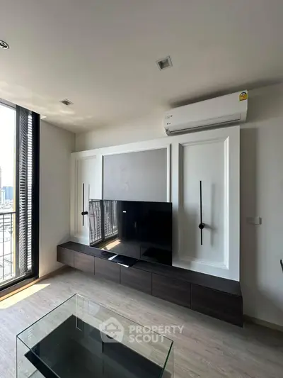 Modern living room with sleek TV unit and air conditioning, featuring a glass coffee table and balcony view.