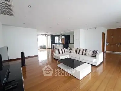 Spacious modern living room with sleek wooden flooring and stylish white sofa.