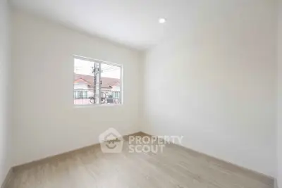 Bright empty room with wooden flooring and large window in modern home