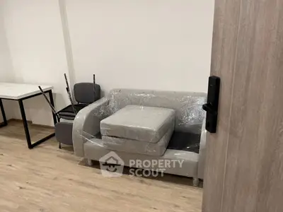 Modern living room with wrapped sofa and chairs, ready for move-in.