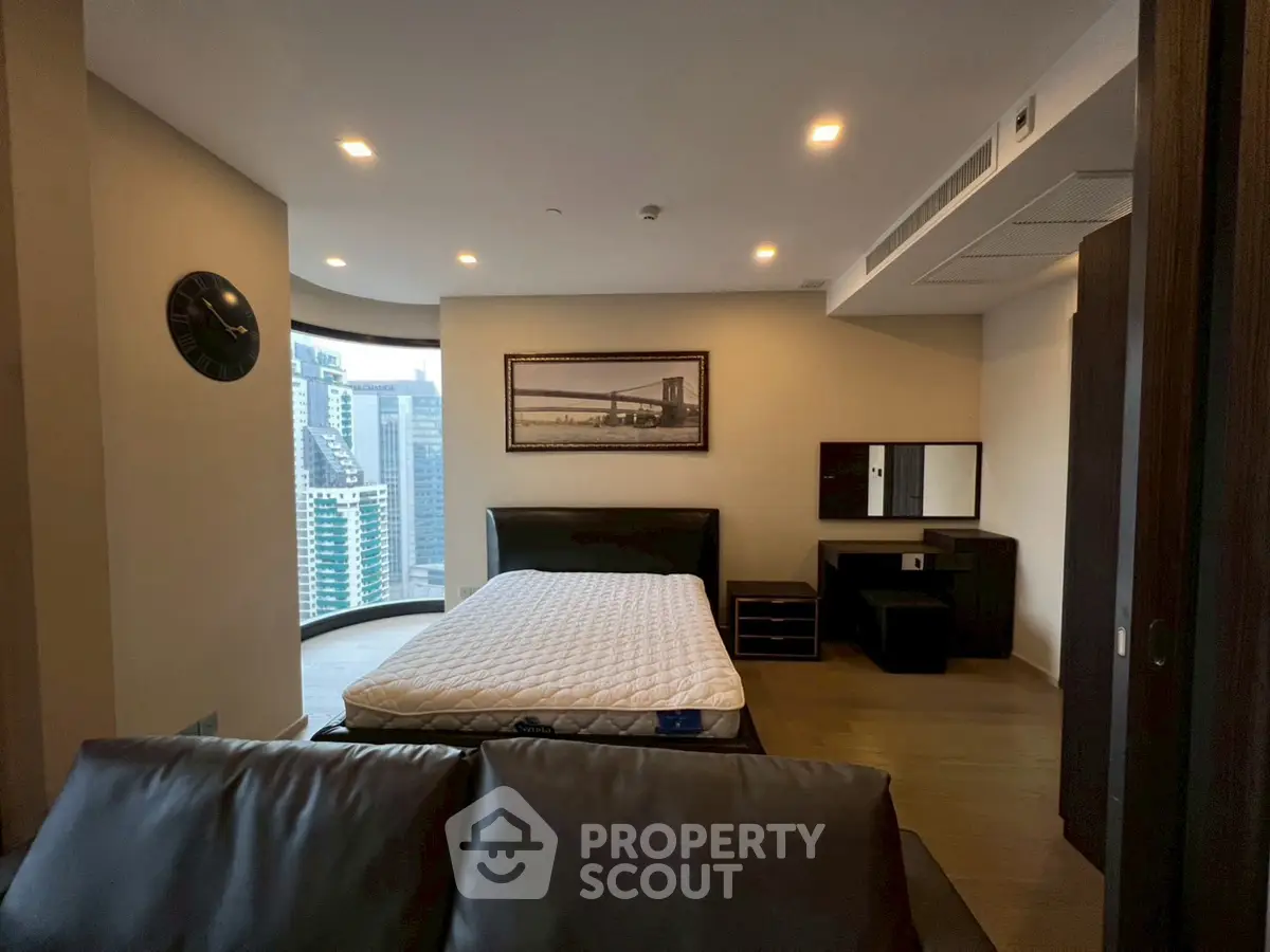 Luxurious bedroom with city view and modern furnishings in high-rise apartment.