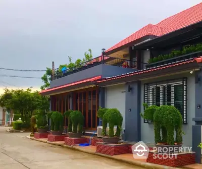 Charming suburban house with red roof and topiary garden, perfect for family living.