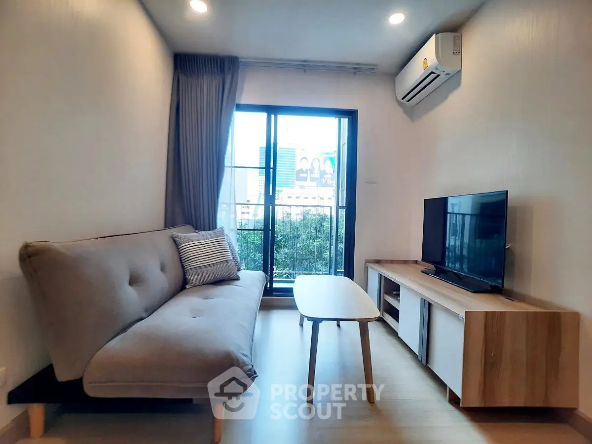 Modern living room with cozy sofa, TV, and large window offering city view.
