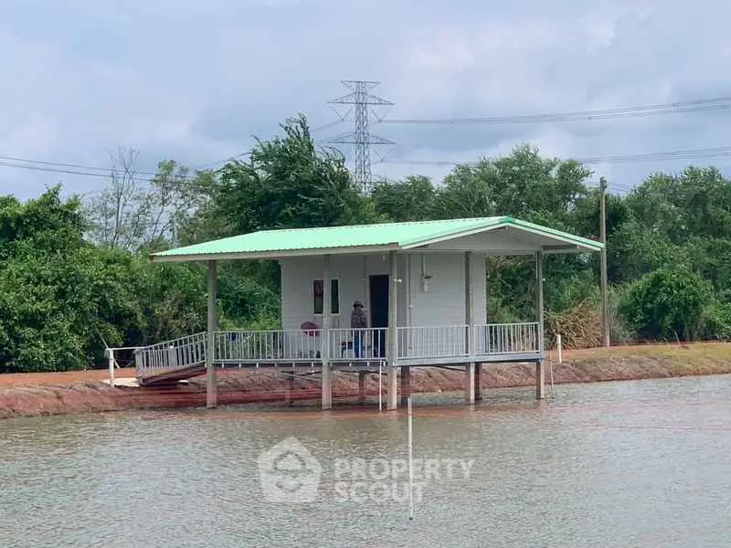 Charming waterfront property with a green-roofed house on stilts, surrounded by lush greenery and serene water views.