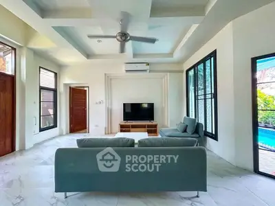 Spacious living room with modern design and pool view, featuring sleek furniture and large windows.