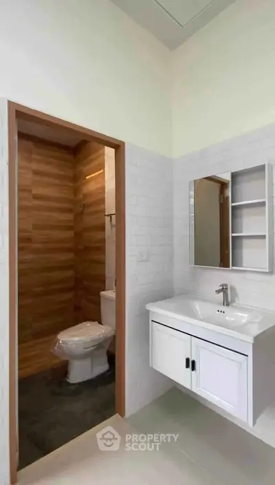 Modern bathroom with sleek white vanity and wood-accented walls, perfect for a contemporary home.