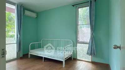 Bright bedroom with minimalist decor and large windows overlooking greenery.
