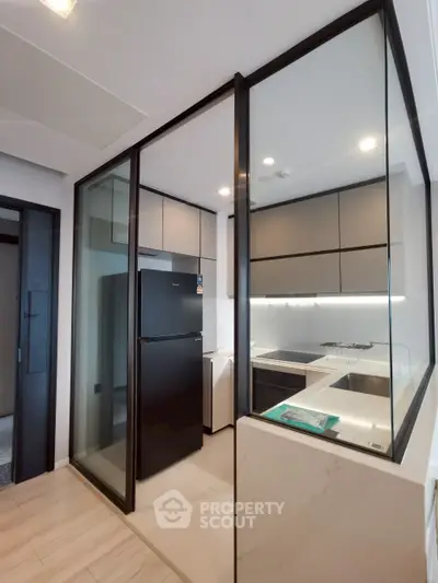 Modern kitchen with sleek glass partitions and black appliances in a contemporary apartment.