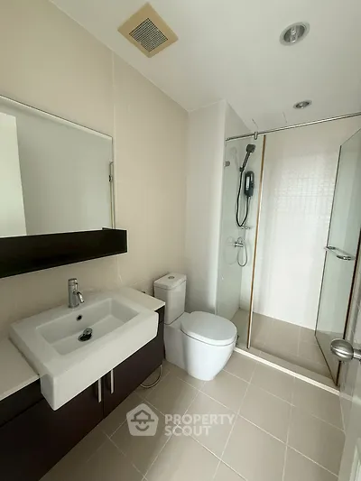 Modern bathroom with sleek fixtures and glass shower enclosure in a contemporary apartment.