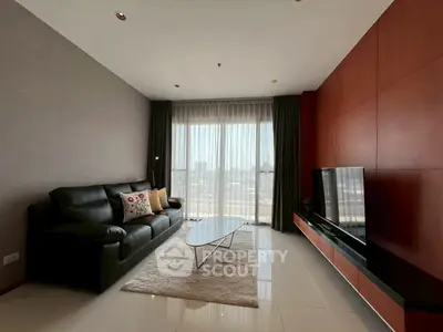 Modern living room with sleek furniture and large window offering city view.