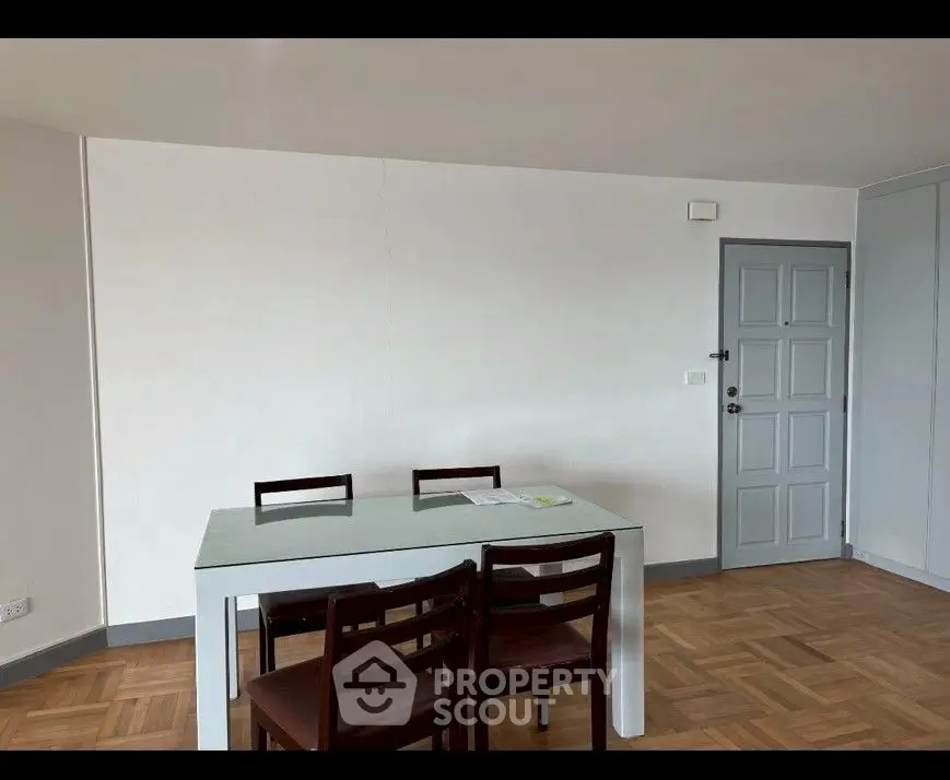 Minimalist dining area with wooden chairs and table on parquet flooring.