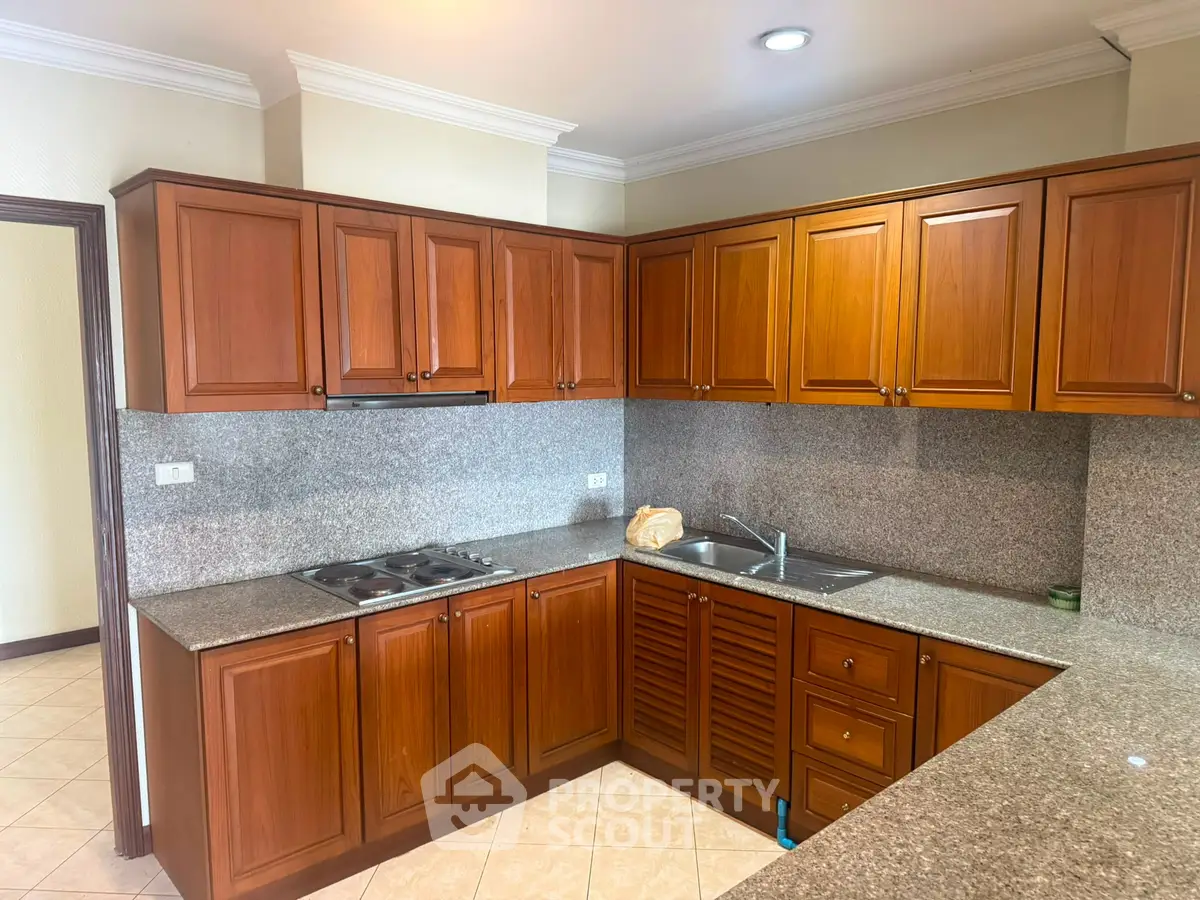 Spacious kitchen with wooden cabinets and granite countertops in a modern home.