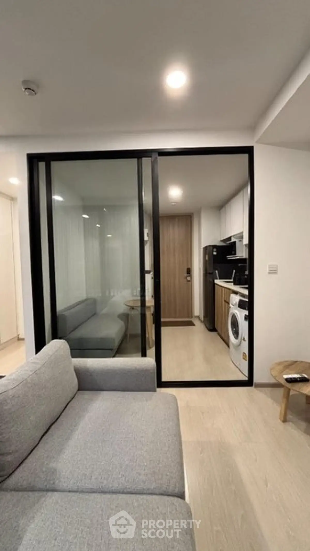 Modern living room with sliding glass door to kitchen, featuring sleek furniture and appliances.