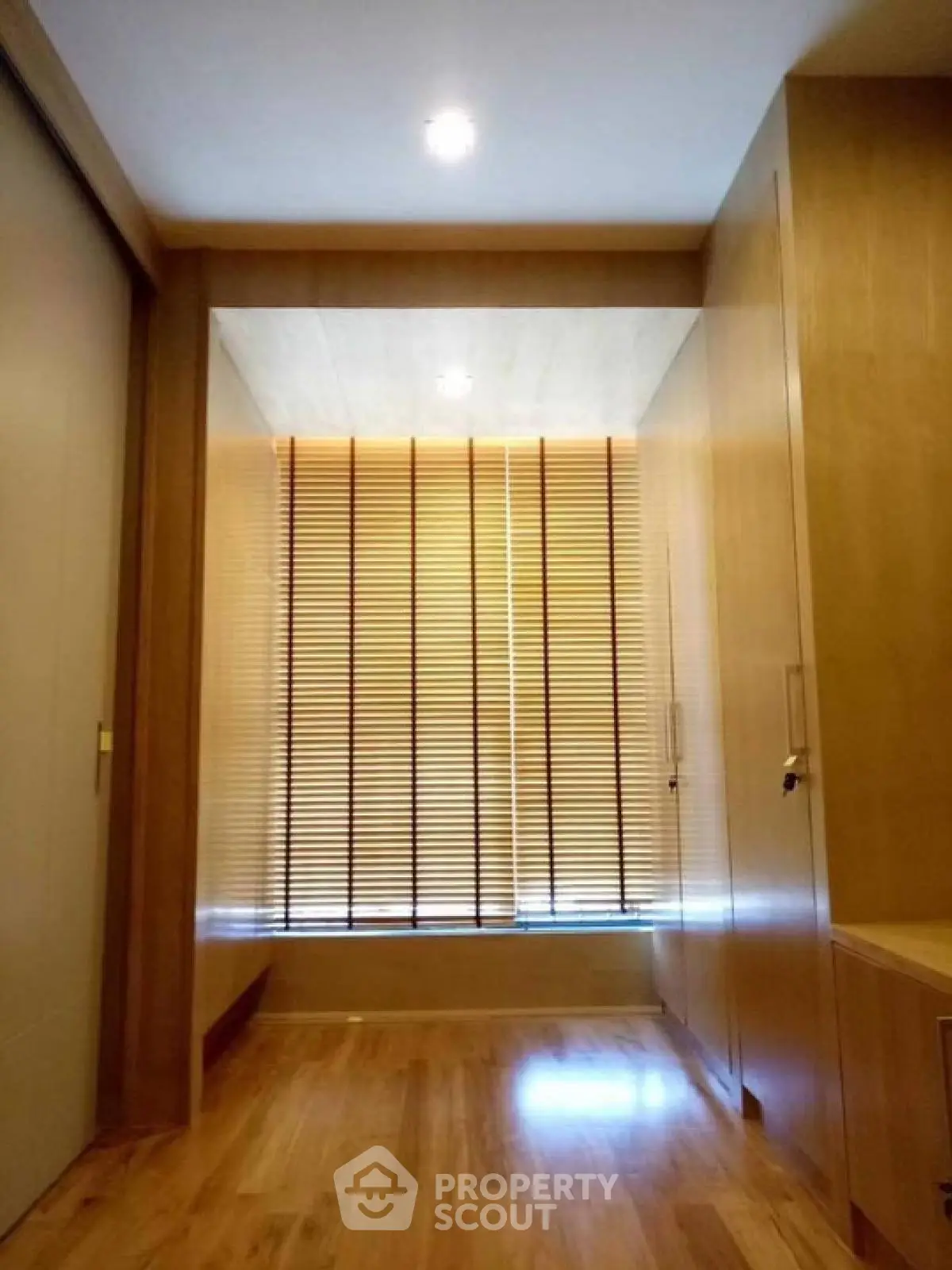 Elegant walk-in closet with wooden flooring and modern blinds