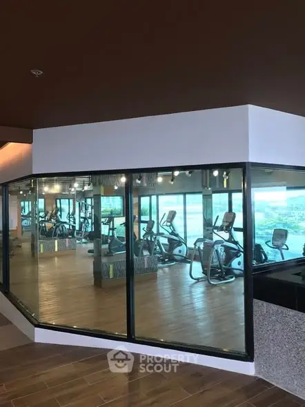 Modern gym with large windows and exercise equipment in a luxury building.