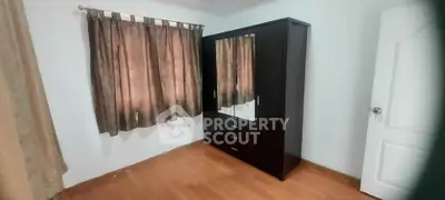 Cozy bedroom with wooden flooring and a sleek wardrobe, perfect for modern living.