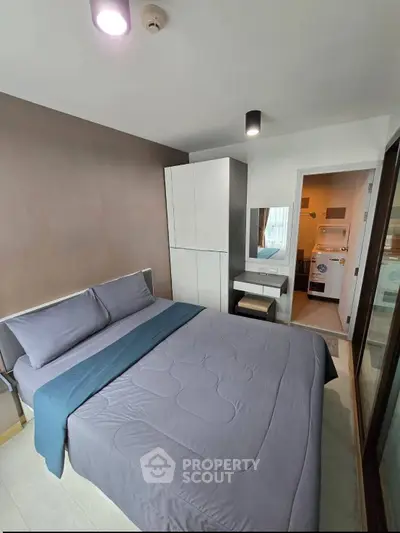Modern bedroom with cozy bed and adjacent laundry area in stylish apartment.