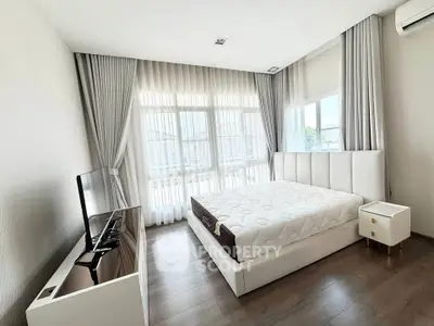 Spacious bedroom with modern decor and large windows offering natural light.