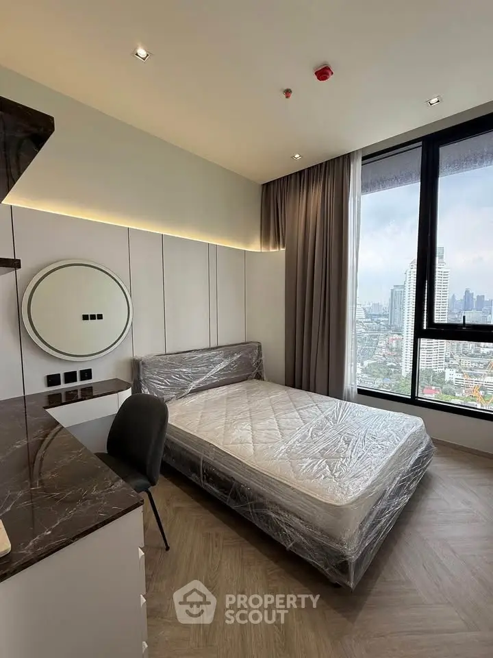 Modern bedroom with city view, featuring a large window and sleek furnishings.