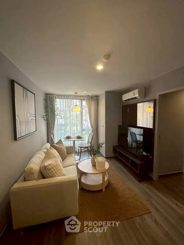 Cozy living room with modern decor, featuring a comfortable sofa, stylish coffee table, and natural light from large windows.