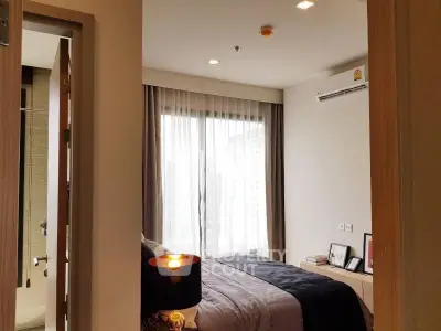 Modern bedroom with large window and city view, featuring elegant decor and ambient lighting.