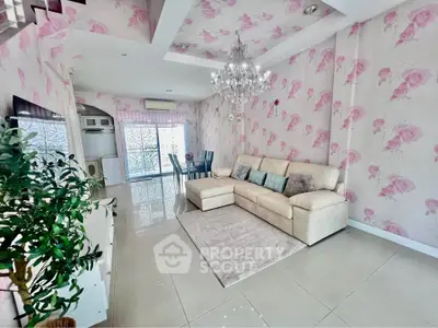 Elegant living room with floral wallpaper, chandelier, and cozy beige sofa