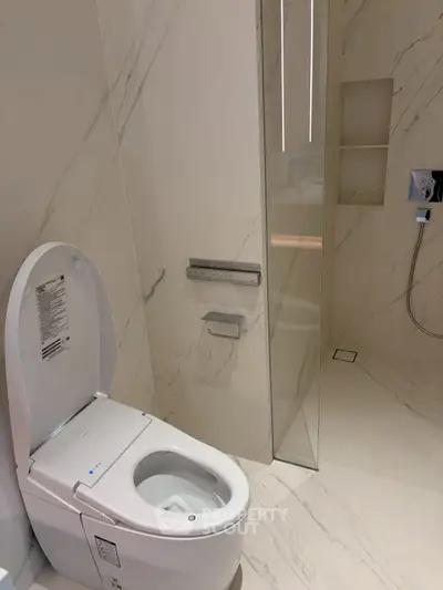 Luxurious modern bathroom with sleek marble design and high-tech toilet features.