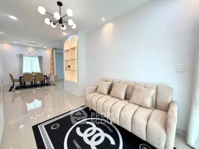 Elegant living room with modern chandelier and plush sofa, leading to a stylish dining area with natural light.