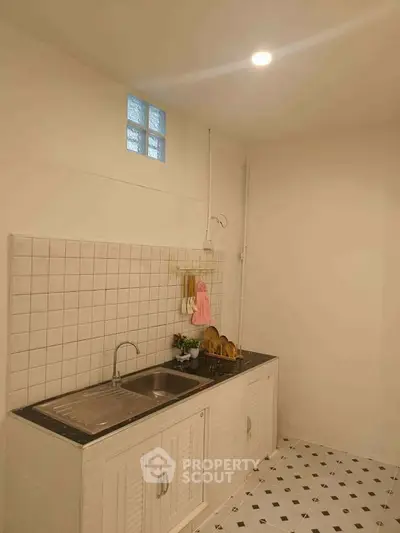 Cozy kitchen with white tiled backsplash and modern sink in minimalist design.