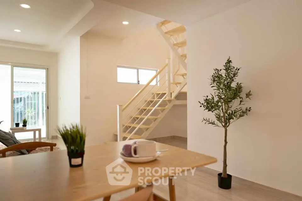 Modern open-plan living area with staircase and natural light